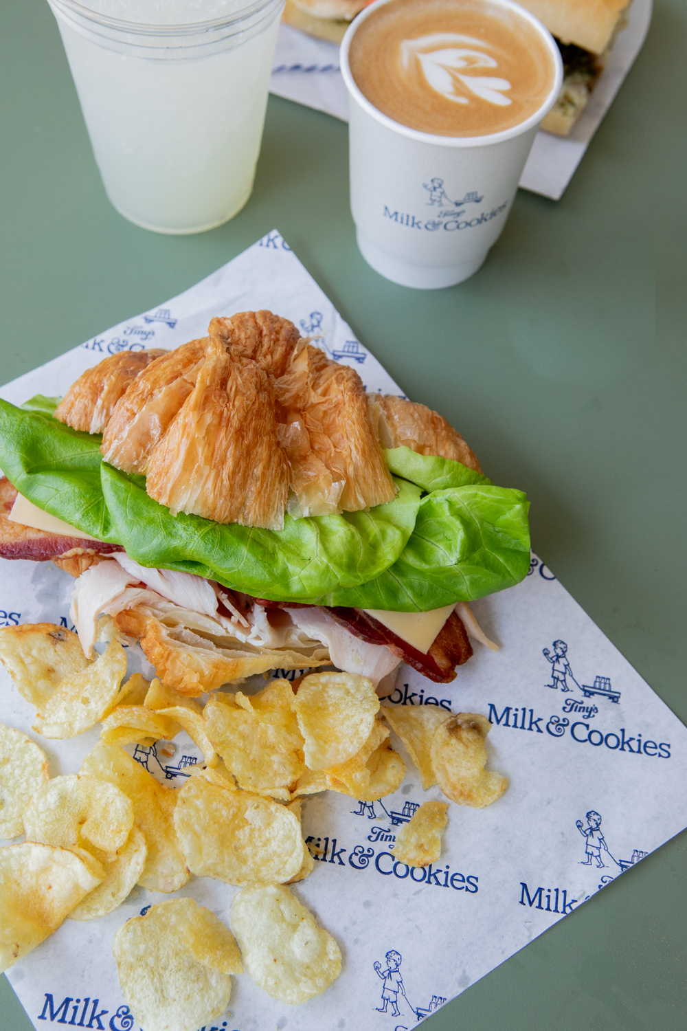 Lunch sandwich, chips, and coffee on green bistro table
