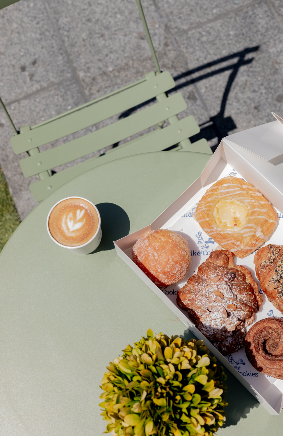 Green bistro table with pastry box and latte