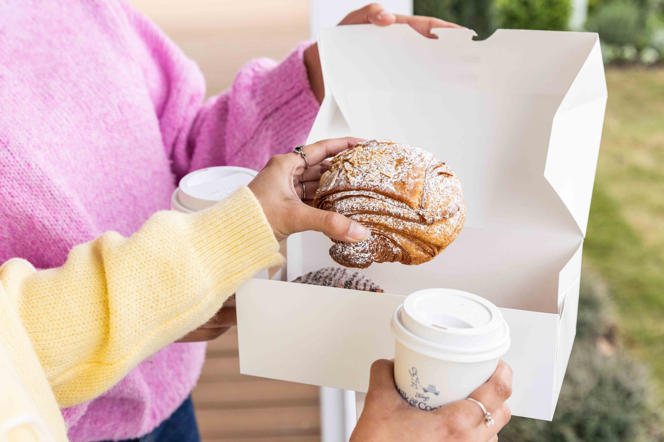 Two Guests Holding Pastry Box and Coffee